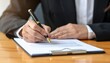 © diditlagi - Close Up Of A Person's Hand Writing With A Pen On A Document At A Wooden Desk