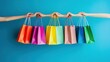 © Kumblack - Hands holding colorful shopping bags against a solid blue background.