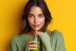 © thiquynh - A woman drinking green juice through a straw, against a solid color background