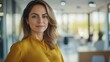 © kirania - A woman is standing and smiling in an office environment