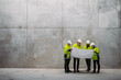 © Halfpoint - Team of engineers and construction workers reviewing blueprints, building site.
