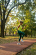 © Nenad - Fit mature woman jumping and running. Healthy female athlete doing fitness workout. Sportswoman raising leg, do functional training outside on bright sunny day, smiling pleased, wearing sport
