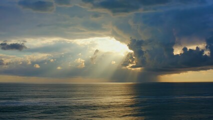 Poster - Streaks of golden sunlight breaking through storm clouds over sea Dramatic lig