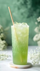 Poster - Refreshing green beverage with ice cubes and straw on marble coaster against a green background and white flowers providing a refreshing and vibrant visual experience