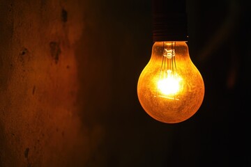 Poster - Illuminated incandescent bulb casting warm glow against textured wall creating vintage ambiance and evoking nostalgia with dramatic lighting in dark room