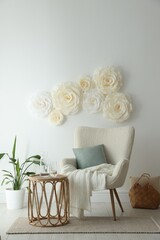 Poster - Beautiful decorative paper flowers on white wall and stylish furniture indoors