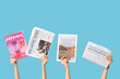 © Pixel-Shot - Female hands with different magazines and newspapers on blue background