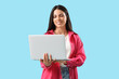 © Pixel-Shot - Beautiful woman using laptop on blue background