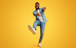 © Prostock-studio - Funny african american guy dancing and extending his hands to camera over yellow studio background, low-angle view