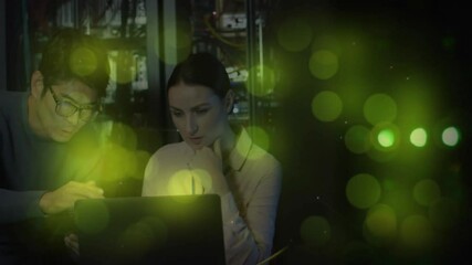 Poster - Two IT experts leaning over laptop in server room, displaying animated cable overlays, green lights