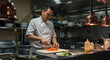 © Mauricio - Professional asian chef preparing food in commercial kitchen restaurant setting