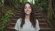 © Bella - Woman smiles warmly in a forest setting.  She stands on a wooden staircase amid lush greenery