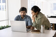 © fizkes - Two Indian teammates analyze data, working on joint project using modern laptop, look at spreadsheets, reports, or analytics, making decisions, solve work-related matters, generate business strategy