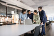 © fizkes - Four young multiethnic professionals gathered around laptop in corporate office, exchanging point, opinion or ideas, listening Indian female guiding, provides explanation regarding software or task