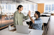 © fizkes - Two happy Indian employees giving high five during meeting in coworking office, greeting each other, start or accomplish teamwork, celebrate milestone achievement, expressing appreciation and respect