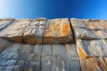 Poster - A majestic cliff face reveals layers of grey and orange rock, textured by time and elements.