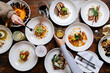 © Cavan Images - Two female hands reaching over tabletop food spread
