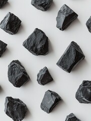 Leinwandbilder - Overhead shot of scattered black rocks on white background forming a pattern.