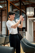 © bongkarn - Asian man wearing glasses in white t shirt is taking photos on his camera in the cafe or coffee shop