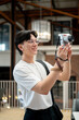 © bongkarn - Asian man wearing glasses in white T shirt is smiling while holding his camera taking a photo in the cafe or coffee shop.