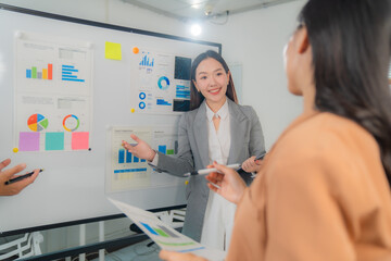 Aufkleber - Two asian businesswomen are discussing and presenting financial charts and graphs on a whiteboard during an office meeting, sharing insights and collaborating on business strategies