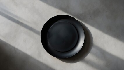 Poster - Unfilled black plate resting on a light gray concrete background. Bird's-eye view.
