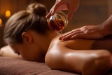 A therapist is pouring hot chocolate massage oil onto a young woman