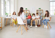 © Studio Romantic - Friendly young psychologist woman having conversation with a group of cute teenage children. School students sitting on sofa with female teacher and having mental health lesson. Psychology concept.
