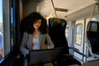 © DusanJelicic - Young businesswoman working on a laptop while enjoying a comfortable train journey, highlighting the blend of modern commuting and productivity in todays professional landscape