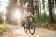 © Andrei - Wellness in motion, a vibrant woman pedals her way through a peaceful forest retreat at sunset