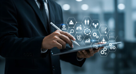 Poster - Businessman in Suit Utilizing Digital Tablet with Interactive Icons in Blue Tones at a Bright Modern Office