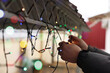 © New Africa - Man decorating house with Christmas lights outdoors, closeup