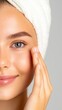 © Pixelbiz - Self care routine wellness healthy skin. A woman with clear skin and a towel on her head gently touches her face, showcasing a fresh, healthy complexion.