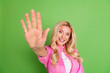 © deagreez - Smiling blonde woman in pink shirt making hand gesture against green background representing positivity and casual lifestyle