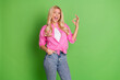 © deagreez - Cheerful blonde woman in stylish pink shirt showing an OK hand gesture while smiling against a vibrant green background