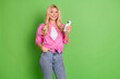© deagreez - Smiling Young Woman Showing Smartphone with Stylish Casual Outfit on Solid Green Background