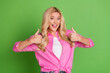 © deagreez - Smiling woman with long blonde hair in a pink shirt giving a double thumbs-up gesture on a bright green background