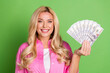 © deagreez - Young blonde woman in casual bright attire showcasing hundred dollar bills and smiling against a vibrant green background