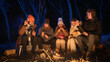 © kinomaster - Friends sitting around a campfire in the woods on a winter evening