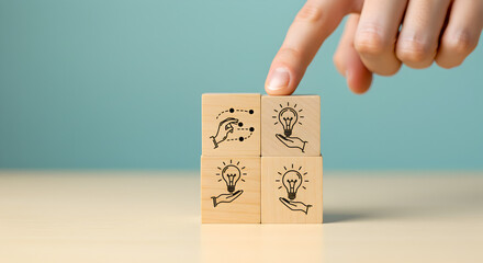 Poster - Close Up of Hand Touching Wooden Cube Blocks Displaying Lightbulb Ideas on Table Against Teal Background