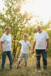 © Serhii - Grandson, grandfather and grandmother sitting on grass having fun outdoors in park at sunset