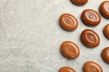 Wall Mural - many tasty caramel candies on grey table, flat lay. space for text