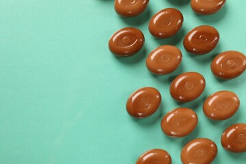 Wall Mural - many tasty caramel candies on turquoise background, flat lay. space for text