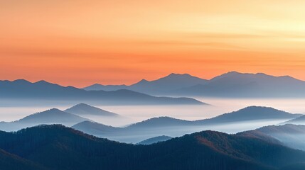 Wall Mural - a sunset view of a mountain range with fog in the foreground and a hazy sky in the distance