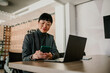 © Zamrznuti tonovi - Asian businesswoman using smartphone and laptop in modern office