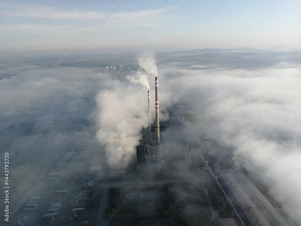 Aerial view of factory chimney emitting smoke above fog layers during ...