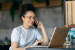 © Dusan Petkovic - Young happy busy freelancer sitting in cafeteria and using her laptop during phone call with client.