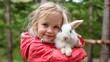 © Pinklife - A delightful girl with a warm smile cradles a white bunny in her arms amidst a lush green forest, embodying the joy of childhood adventures and the bond between human and animal.