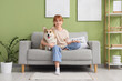 © Pixel-Shot - Teenage redhead girl with Corgi dog sitting on sofa at home