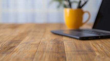 Poster - Modern laptop placed next to a warm cup of coffee on a wooden surface, creating a cozy workspace vibe